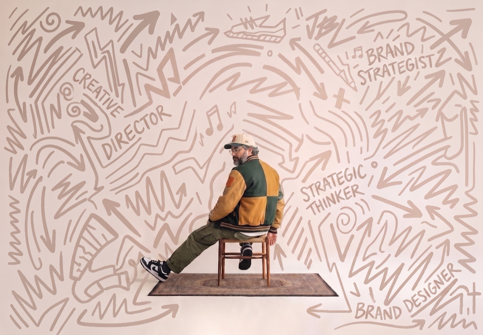 Filipe Sales sitting on a chair in a studio, in front of a wall covered in hand-drawn doodles