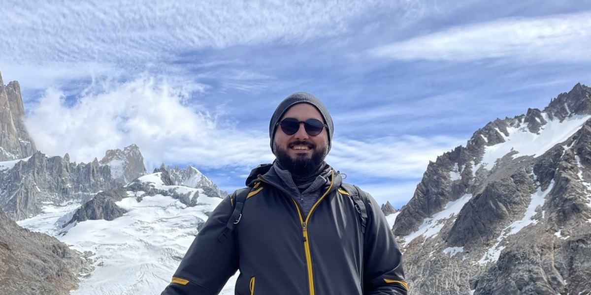 Filipe Sales smiling in a beanie and sunglasses on a mountain trail