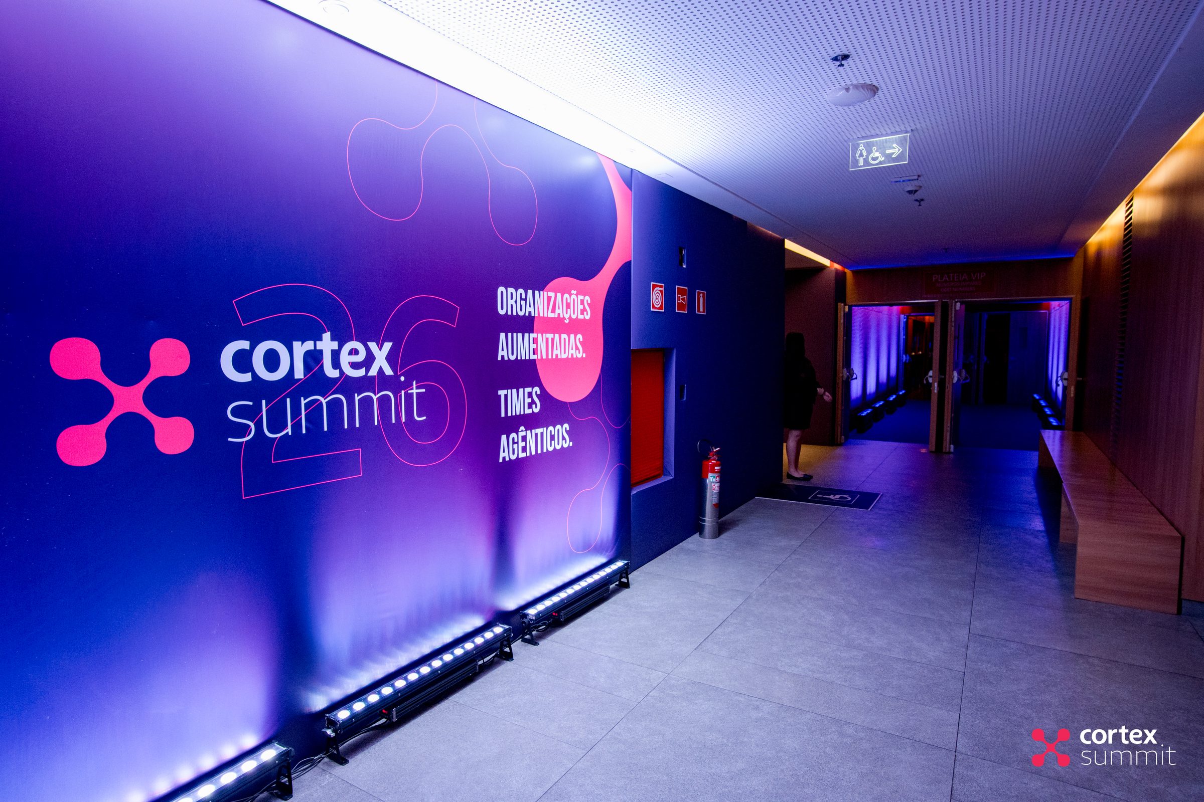 Corridor wall at the theatre with the Cortex Summit logo, an outlined 26 and the Organizações Aumentadas headline