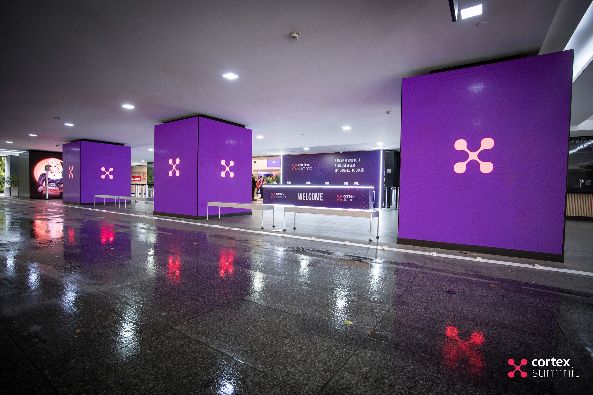 Theatre entrance with purple totems carrying the Cortex Summit symbol, reflected on a wet floor