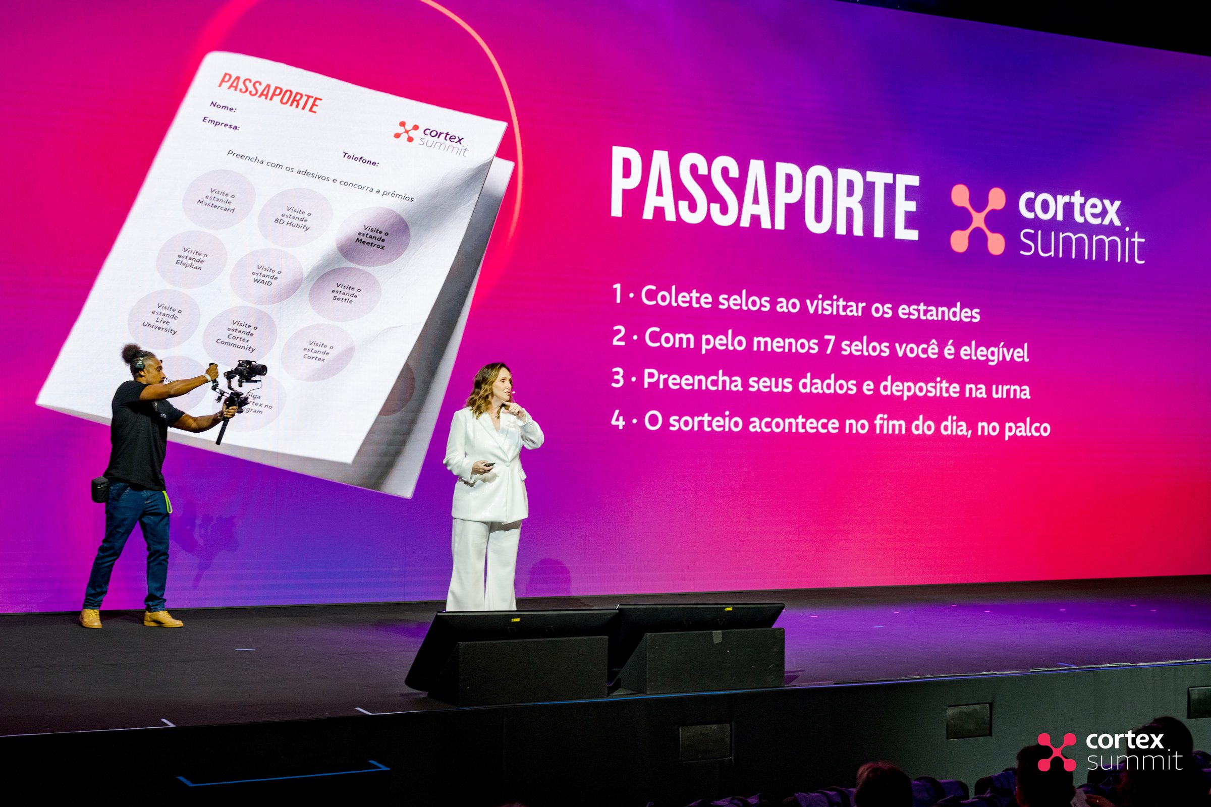 Stage screen presenting the Passaporte activation as a camera operator films
