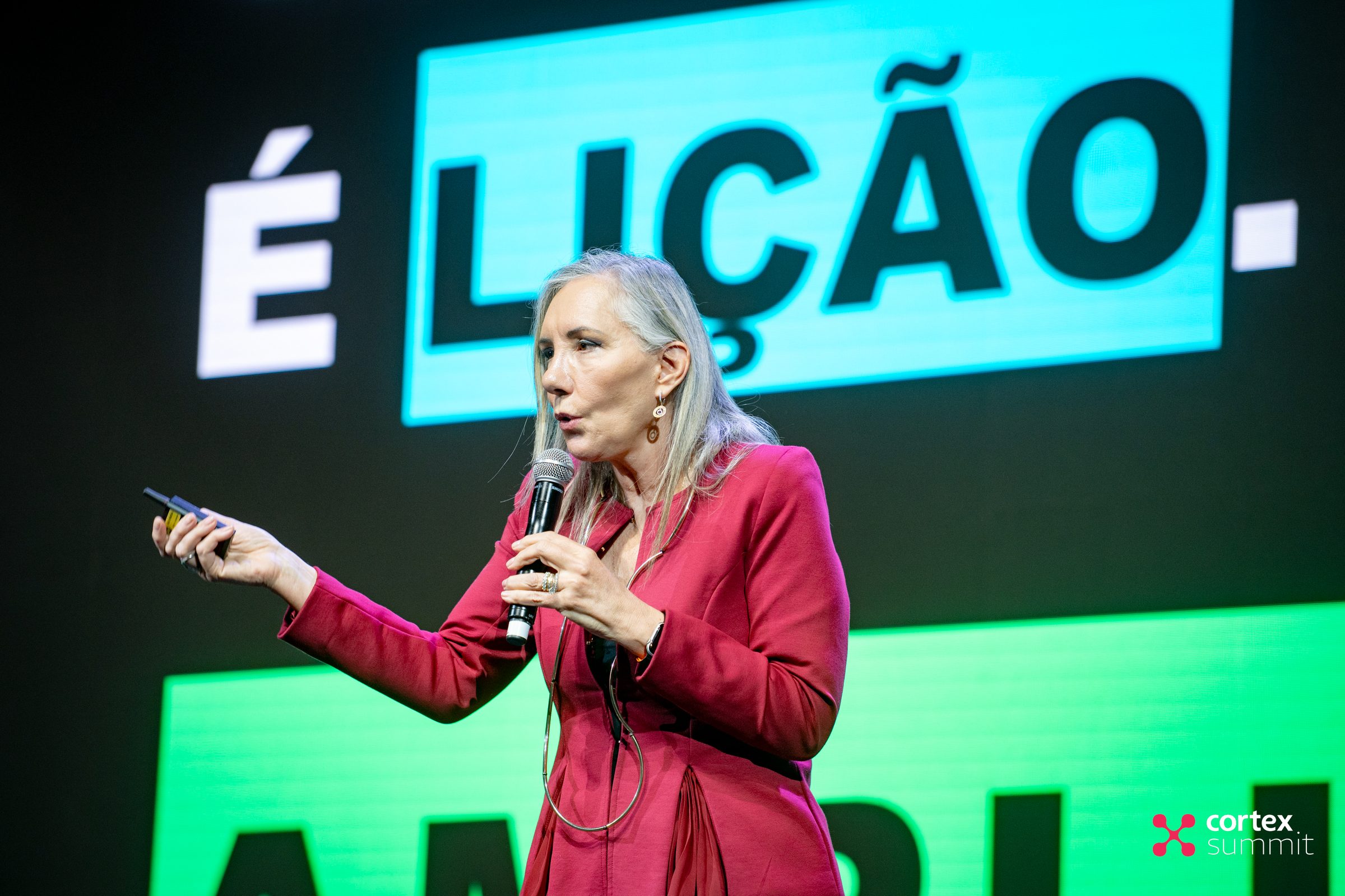 Speaker on stage holding a microphone in front of a mint and white LED backdrop
