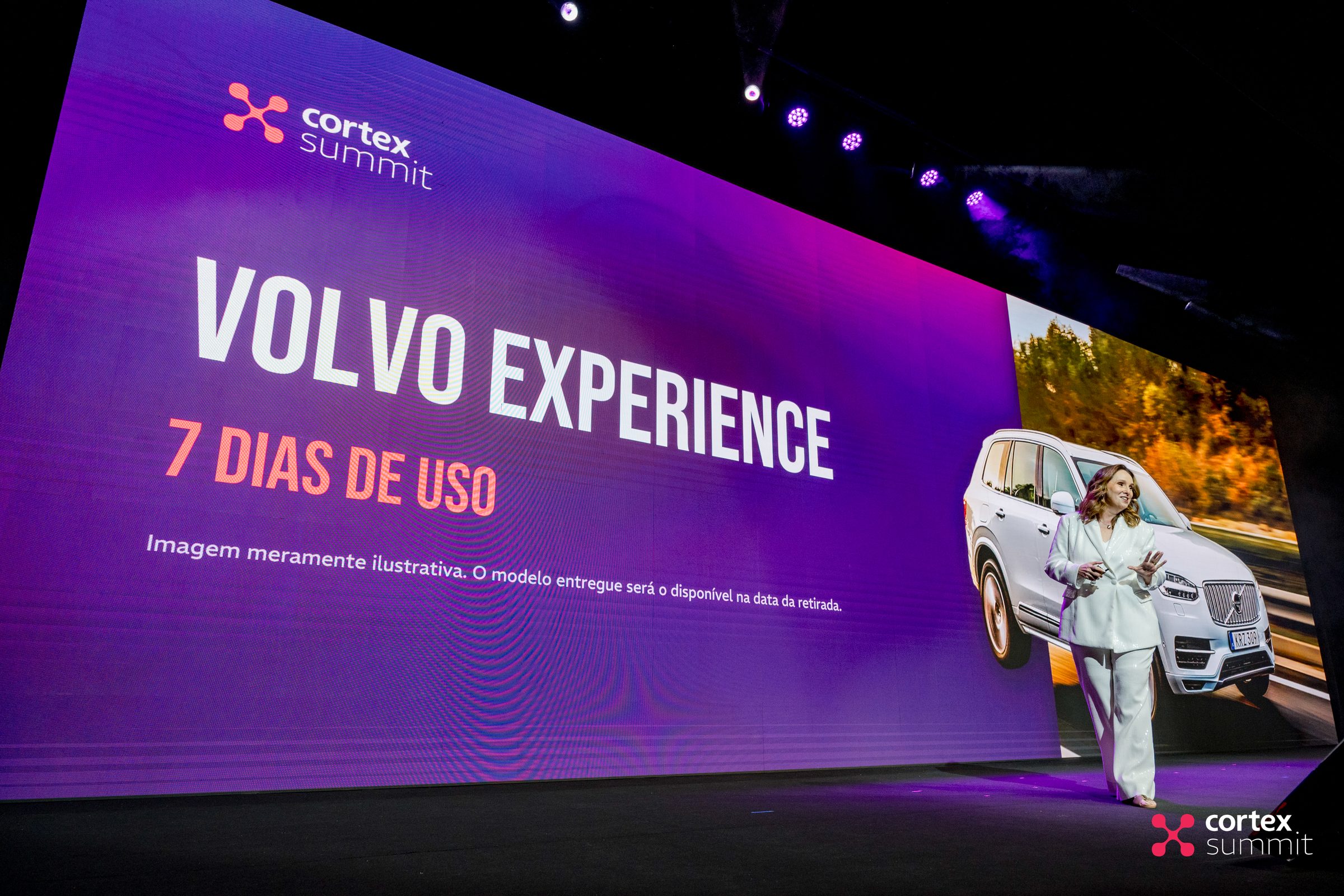Stage screen presenting the Volvo Experience prize with the host beside it