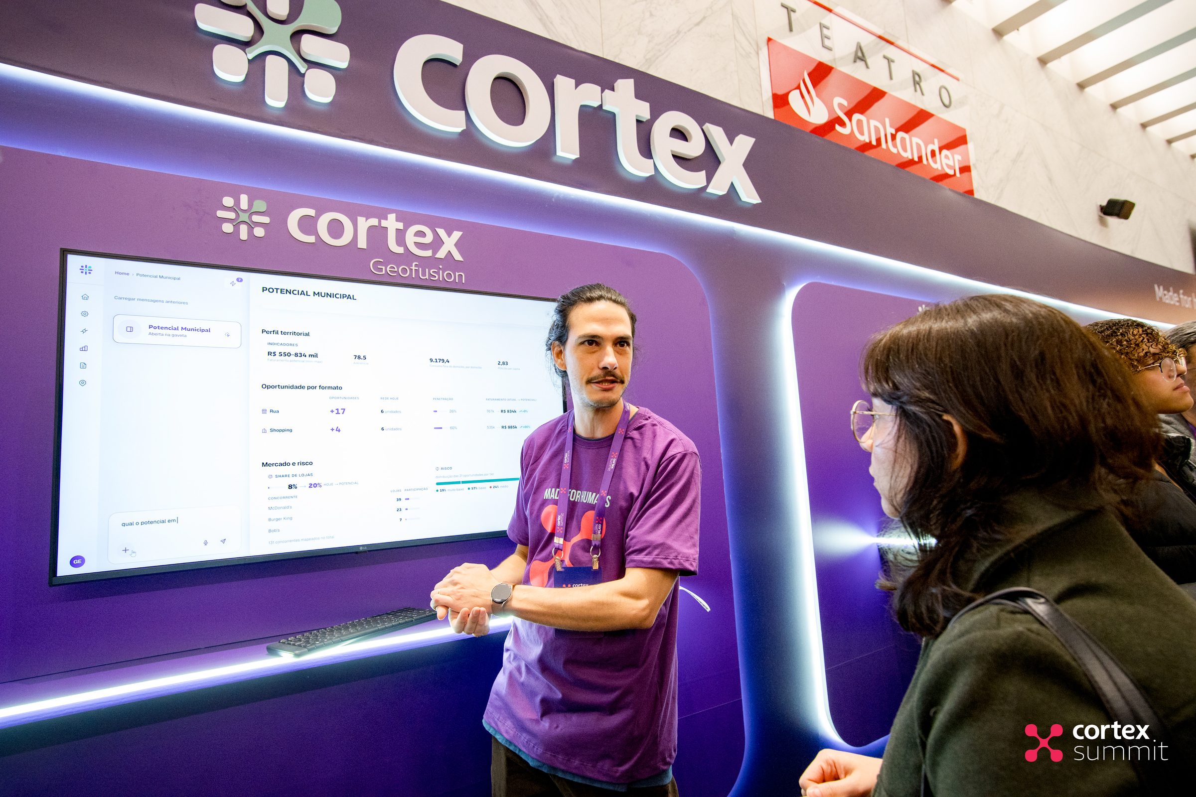 Visitor talking to a Cortex team member in front of a product demo screen at the stand